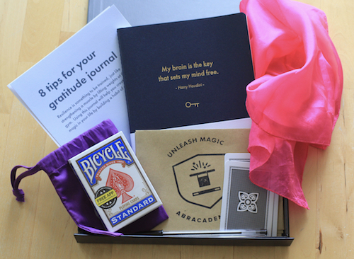 Box showing a pack of playing cards, silk scarf and gratitude journal